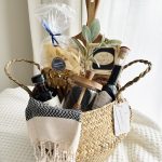 Luxury housewarming gift basket titled The Heart of Gathering by Divine Bloom Sarasota, featuring a solid wood serving board, premium Italian pappardelle pasta, artisanal biscotti, a glass honey jar with a wooden dipper, and modern turkish hand towel.