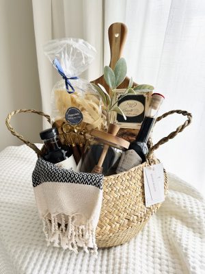 Luxury housewarming gift basket titled The Heart of Gathering by Divine Bloom Sarasota, featuring a solid wood serving board, premium Italian pappardelle pasta, artisanal biscotti, a glass honey jar with a wooden dipper, and modern turkish hand towel.