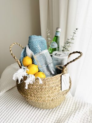 Luxury coastal gift basket titled The Coastal Refresh by Divine Bloom Sarasota, featuring turquoise Turkish towel, fresh lemons, S.Pellegrino bottle, and ribbed glass tumblers with straws.