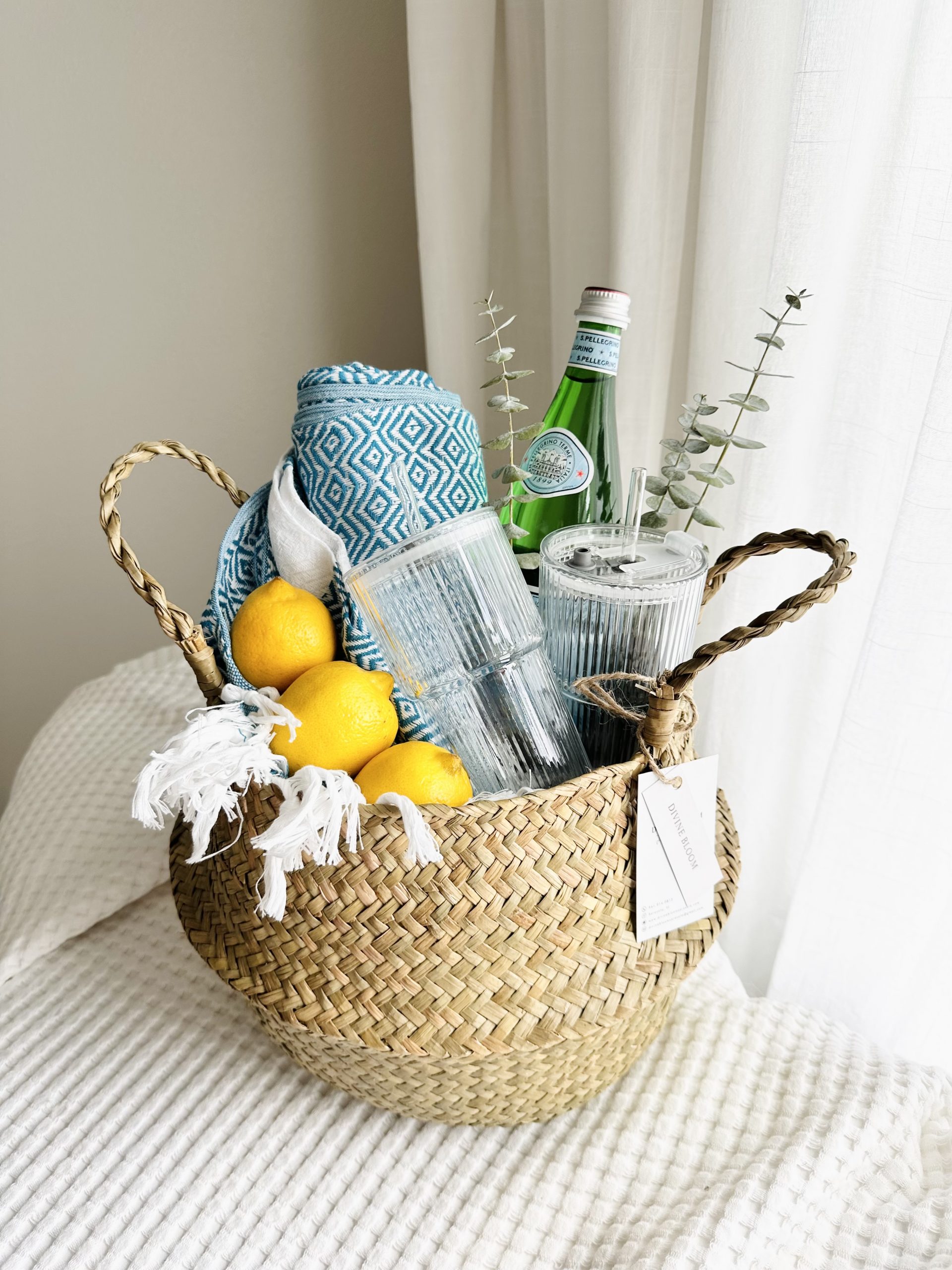 Luxury coastal gift basket titled The Coastal Refresh by Divine Bloom Sarasota, featuring turquoise Turkish towel, fresh lemons, S.Pellegrino bottle, and ribbed glass tumblers with straws.